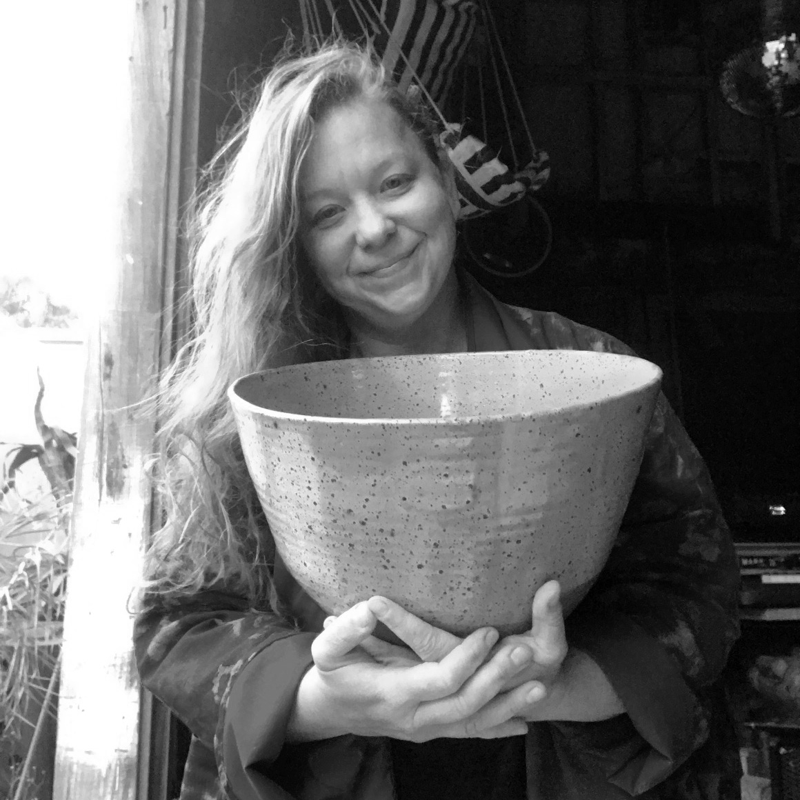 Image of Nicole, a cis-white woman with long hair, holding a large ceramic bowl